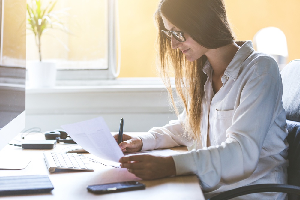 Uma mulher à mesa fazendo anotações, em referência ao investidor qualificado