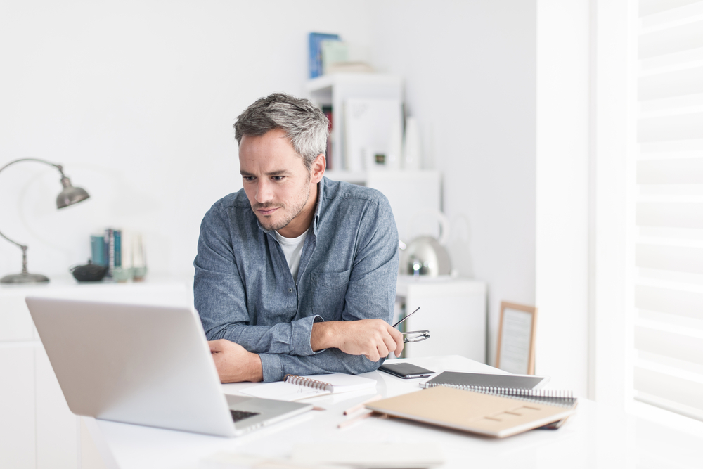 um homem à mesa olhando para o notebook. em referência ao melhor cdb