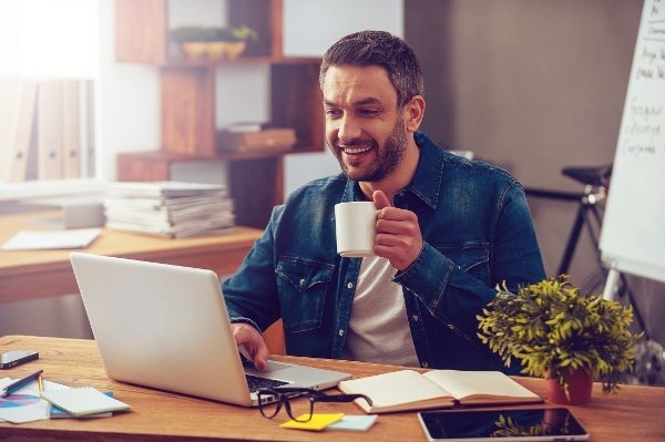 Economia projeções outubro: homem olha para computador com caneca