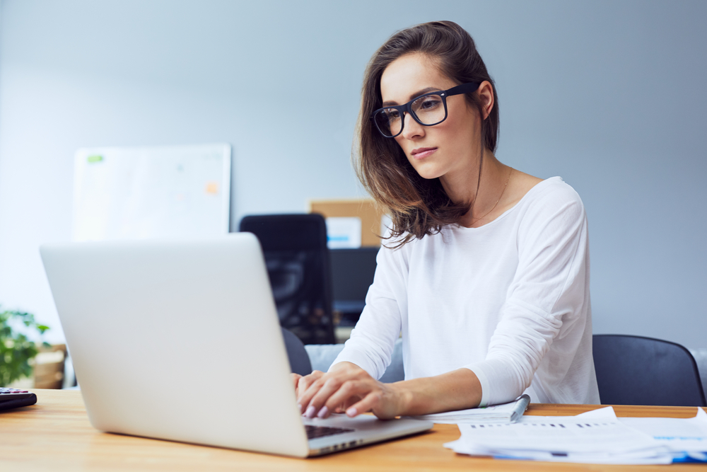 Uma mulher mexendo no notebook em referência à taxa selic hoje