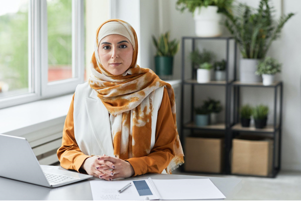 Mulher em frente a uma mesa, com um notebook, pesquisando como investir em coe.