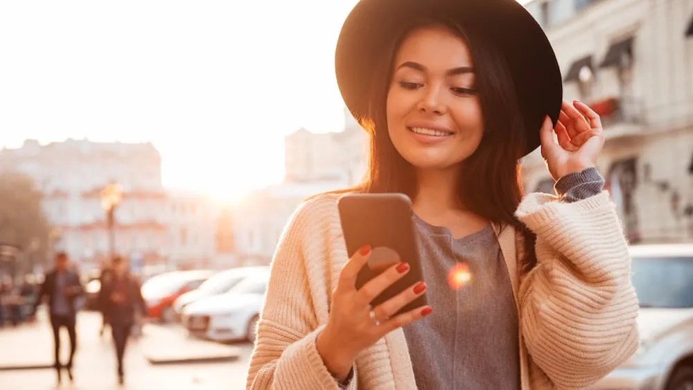 Jovem mulher no centro da cidade utilizando seu smartphone para cadastrar uma nova chave Pix.