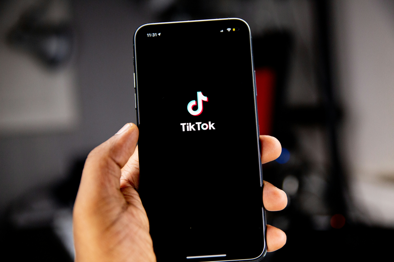 Mão segurando celular com ícone do TikTok na tela