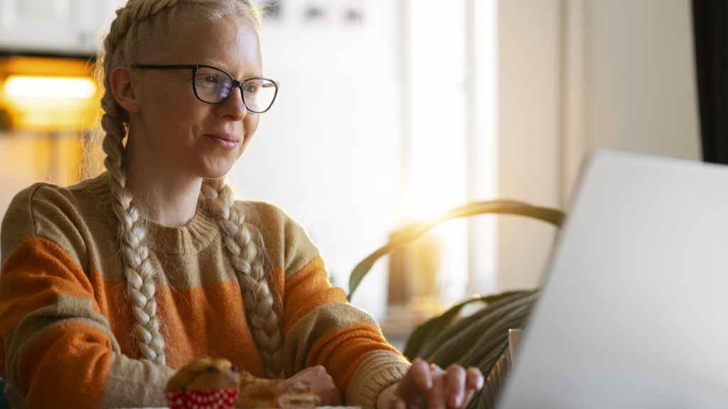 Mulher avalia em seu notebook opções de onde investir 2 mil reais.